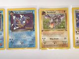 four pokemon cards are lined up on a white surface