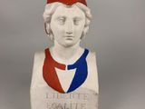 statue of a woman with a red hat and a blue ribbon around her neck