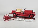 a red toy car on a train track with a red wagon