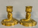 two gold candlesticks sitting on a white surface