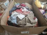a cardboard box full of clothes and a stuffed animal