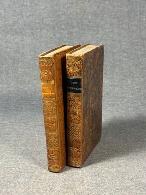 two old books sitting on top of each other on a table