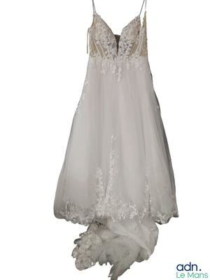 une robe de mariée suspendue à un cintre accroché au mur