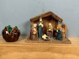 une figurine représentant une crèche et trois autres figurines posées sur une étagère