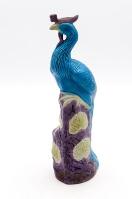 une figurine représentant un paon perché sur un rocher