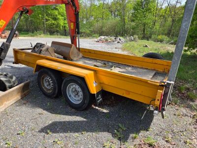 une remorque jaune avec un tracteur et une pelleteuse rouge à l'arrière