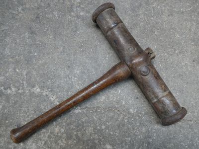 un vieux marteau posé par terre à côté d'un morceau de bois