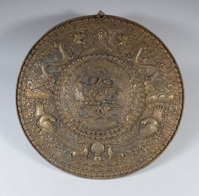 une vieille plaque en laiton ornée d'un motif sur un fond blanc