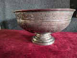 an ornate silver bowl on a red velvet surface