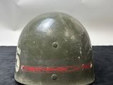 an old helmet with a red stripe on it sitting on a black surface