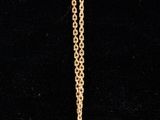 a close up of a gold necklace on a black background