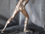 une statue en bronze représentant un homme tenant une raquette de tennis