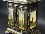 une armoire peinte en noir et or, surmontée d'une horloge