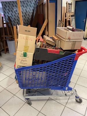 un caddie bleu rempli de cartons au milieu d'une pièce