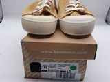 Des Converse beiges à lacets blancs sont posées sur une boîte en carton