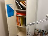 a desk with a lamp and a book shelf in the corner