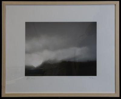 a black and white photograph of a mountain with clouds in the sky
