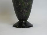 a green vase with a black base sitting on a white surface