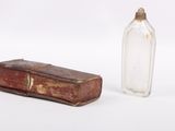 an old book and a glass bottle sitting next to each other