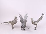 trois oiseaux en métal sont placés les uns à côté des autres sur une surface blanche