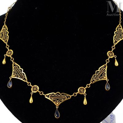 a gold plated necklace with black glass drops on a black mannequin