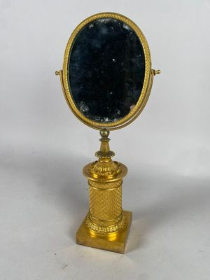 miroir plaqué or avec un verre bleu, posé sur un socle