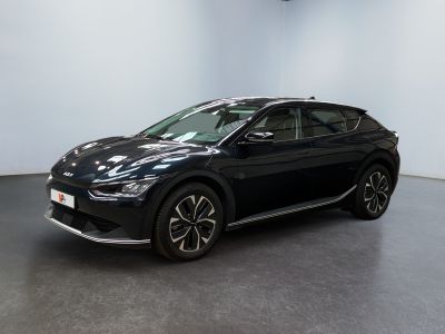 Une voiture noire est garée dans une pièce aux murs blancs