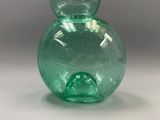 a green glass vase that is sitting on a table