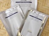 trois paquets de masques pour le visage posés sur un plateau en bambou