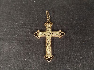 a gold cross with a cross on it sitting on a black surface