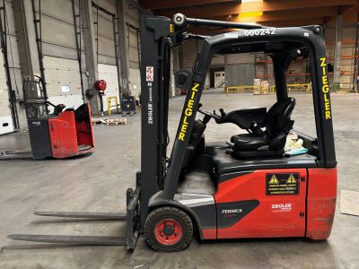 un chariot élévateur rouge garé à l'intérieur d'un entrepôt