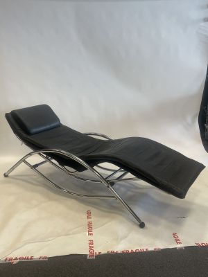 a black leather chaise lounger and ottoman in a studio setting
