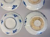 four blue and white plates with blue flowers on them on a table