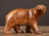figurine d'ours en bois sculpté posée sur une table en bois, sur fond noir