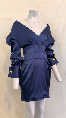 Le mannequin porte une robe bleue ornée de boutons dorés.