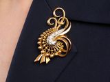 gold tone broochle with a white and clear crystal in the center