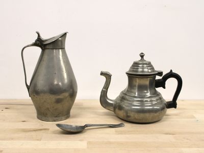 une théière en argent et une théière en argent posées sur une table en bois