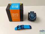 une montre bleue et noire posée à côté d'une boîte noire et orange