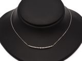 a black necklace with silver beads on a black mannequin