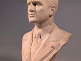 statue of a man in a suit and tie sitting on a table