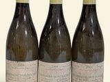 trois bouteilles de vin posées les unes à côté des autres sur une surface blanche