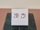 a pair of diamond stud earrings sitting on top of a marble block
