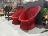 two red wicker chairs and a cat sitting on a chair