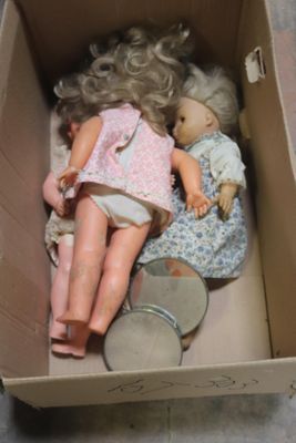 une boîte posée par terre, contenant deux poupées