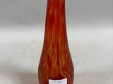 un vase en verre rouge posé sur une surface blanche