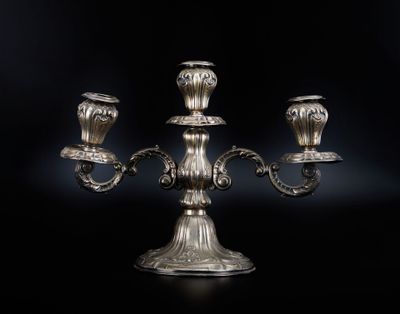 un chandelier plaqué argent avec trois bougies sur fond noir