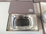 two silver dishes in a box on a table
