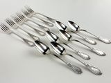 five silver spoons and a comb on a white table