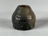 un vase noir et blanc posé sur une surface blanche