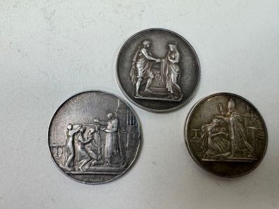 trois pièces d'argent posées l'une à côté de l'autre sur une surface blanche